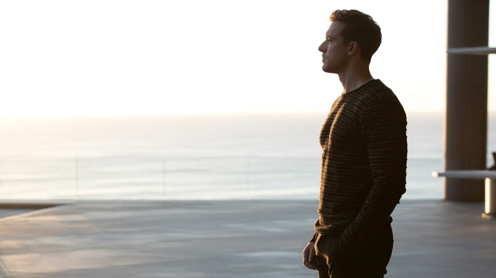 A calm, confident moment looking out over the sea at dawn.